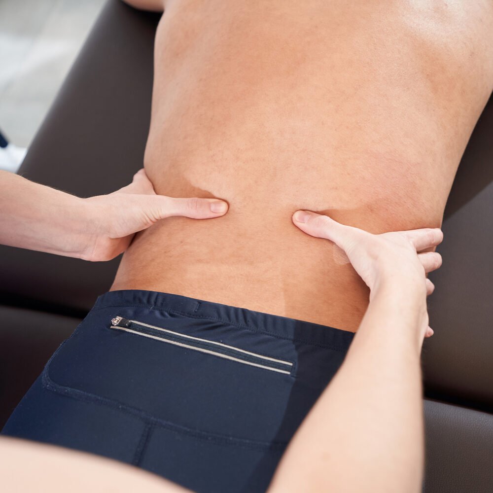 Woman physiotherapist hands massaging male back in clinic Close up of African American man lying on massage table and receiving rehabilitation therapeutic massage