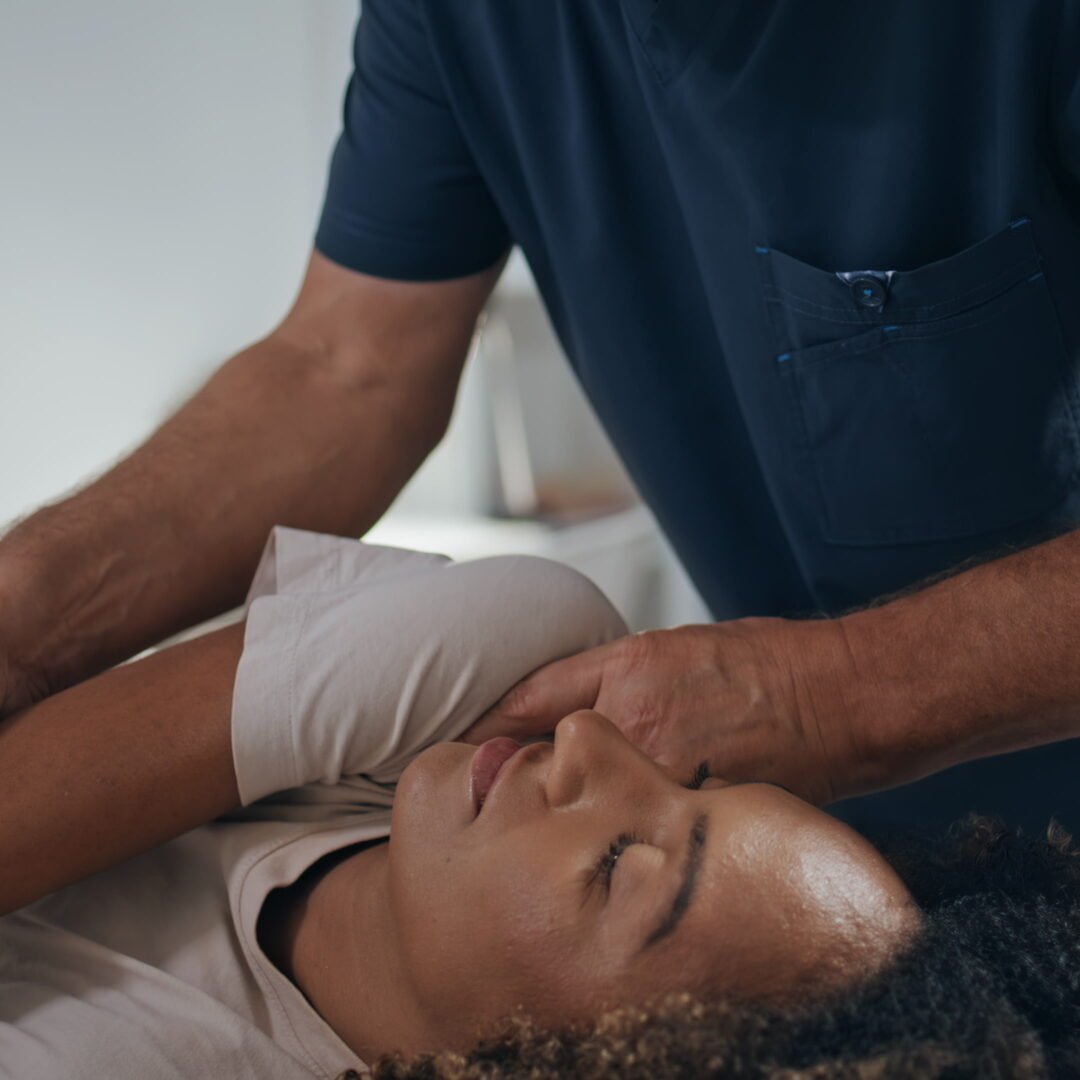 Manual chiropractor treat patient in clinic. Closeup woman visit physiotherapy after trauma. Unrecognizable osteopath doing manipulation stretching back. African american girl on recovery session.